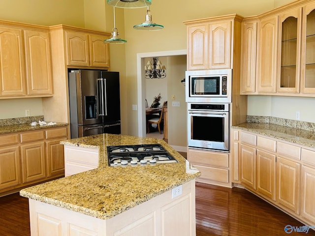 kitchen featuring appliances with stainless steel finishes, light brown cabinetry, a center island, dark hardwood / wood-style floors, and hanging light fixtures