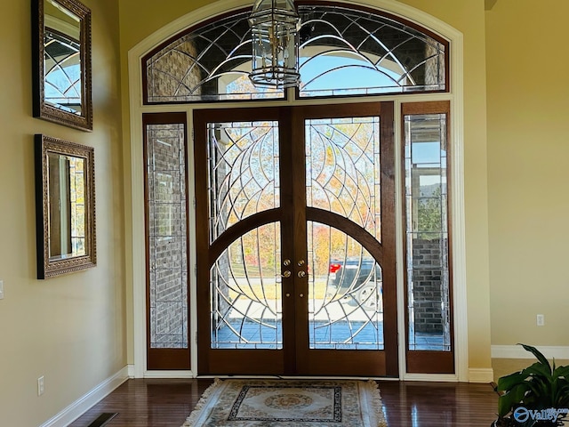 foyer with plenty of natural light, an inviting chandelier, dark hardwood / wood-style flooring, and french doors