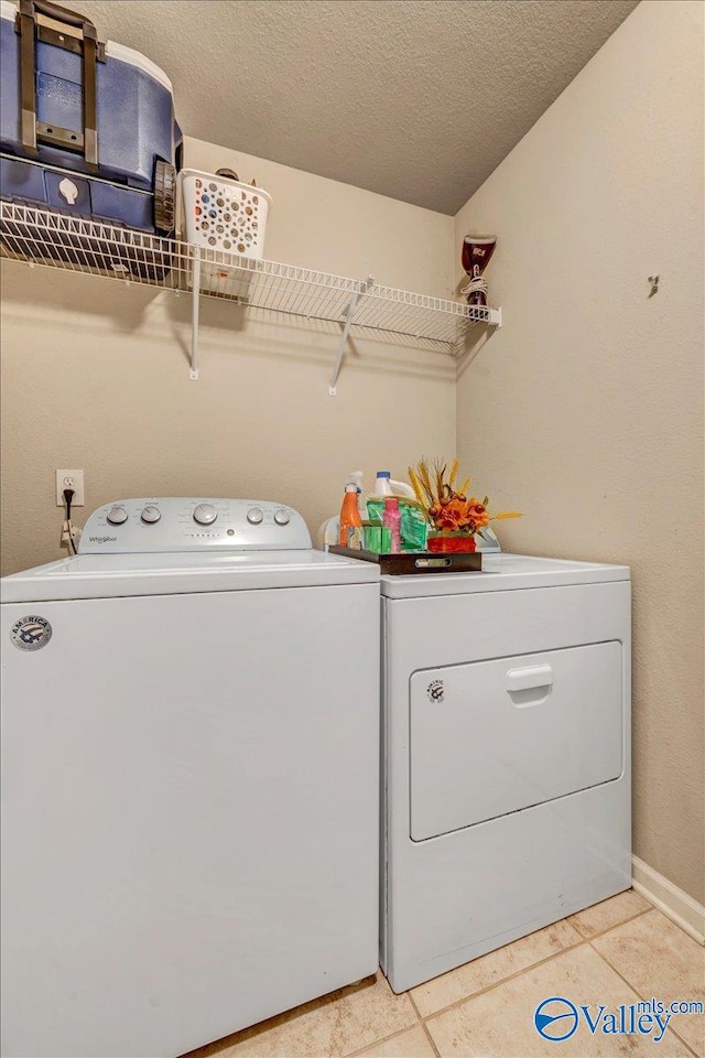 washroom with light tile patterned flooring, a textured ceiling, and separate washer and dryer