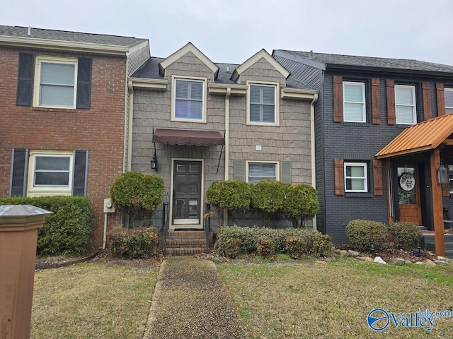 multi unit property featuring a front yard and brick siding