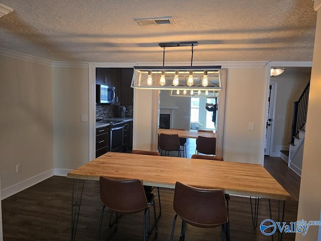 kitchen featuring dark wood finished floors, butcher block counters, stainless steel microwave, visible vents, and range with electric cooktop