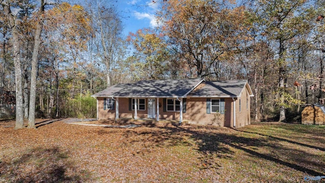 ranch-style home featuring covered porch, a storage shed, and a front yard