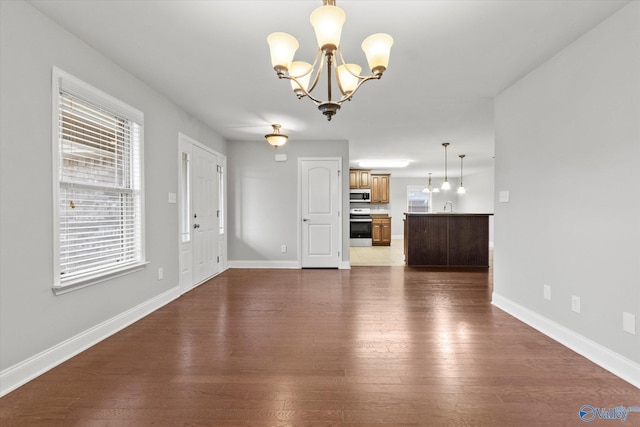 unfurnished living room with sink, dark hardwood / wood-style flooring, and a notable chandelier