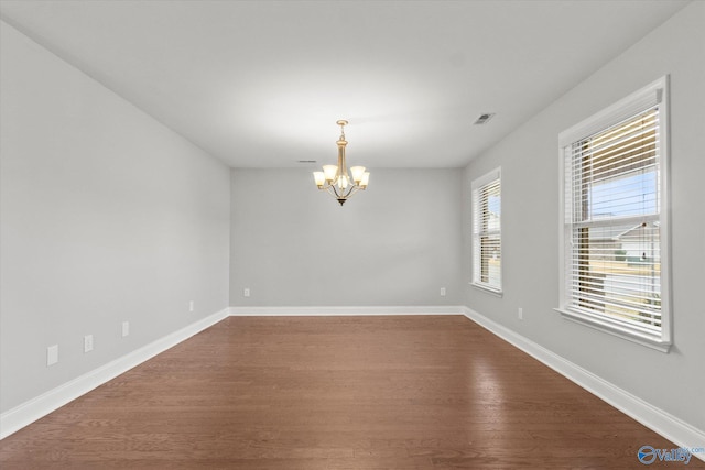 spare room featuring hardwood / wood-style floors and an inviting chandelier