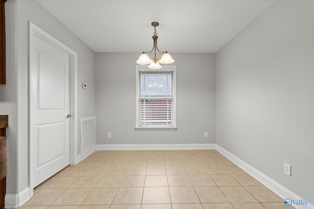 empty room with light tile patterned floors and a notable chandelier