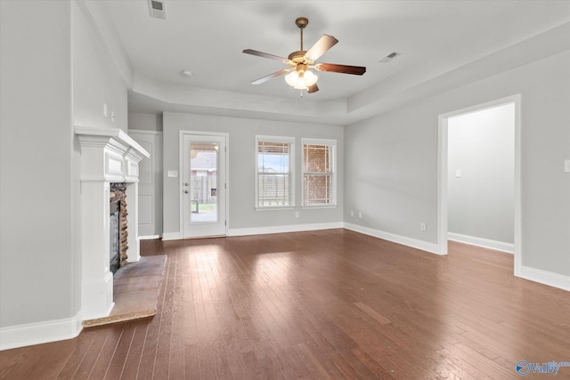 unfurnished living room featuring a fireplace, dark hardwood / wood-style flooring, and ceiling fan