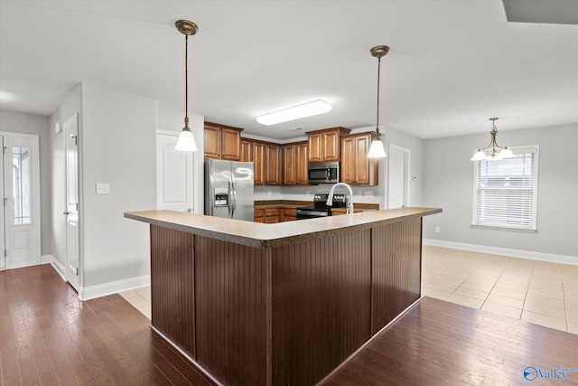 kitchen featuring a breakfast bar, decorative light fixtures, light hardwood / wood-style floors, stainless steel appliances, and a chandelier