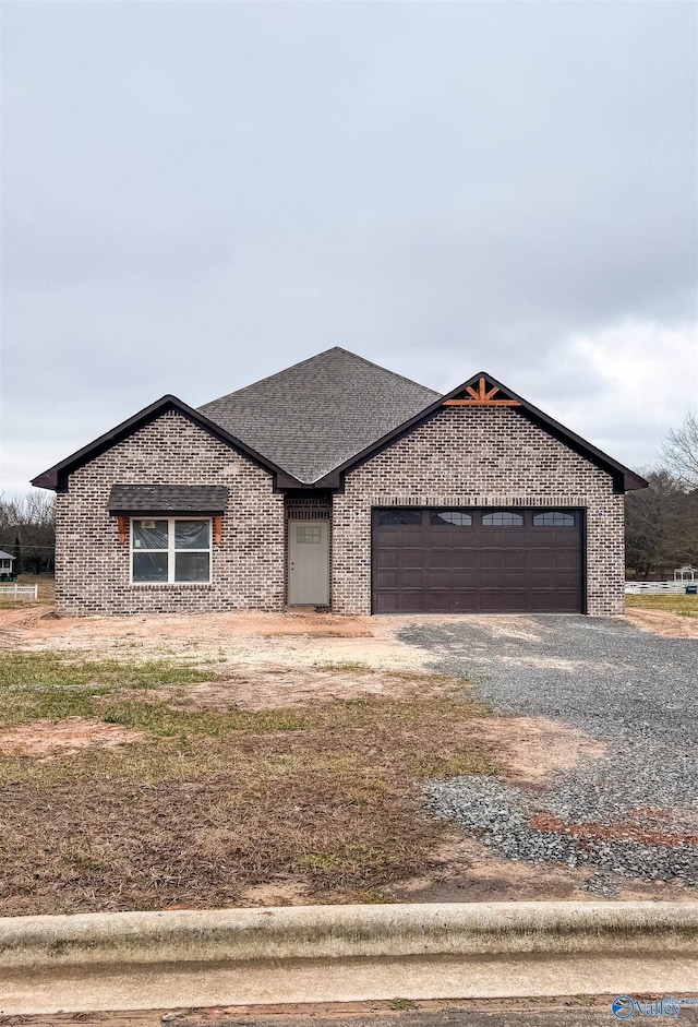 view of front of property featuring a shingled roof, brick siding, driveway, and an attached garage