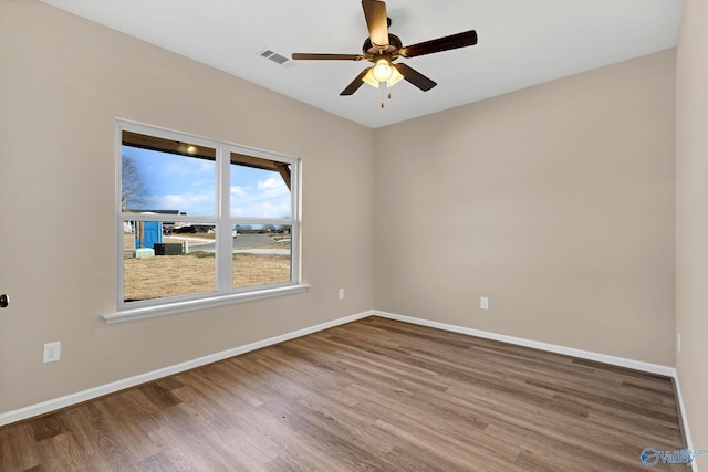 spare room featuring visible vents, baseboards, and wood finished floors