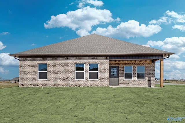 back of property with a shingled roof, a lawn, and brick siding