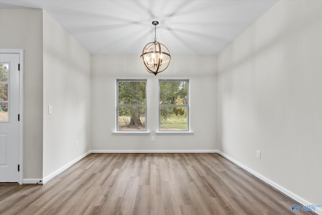 unfurnished dining area featuring a chandelier, wood finished floors, and baseboards