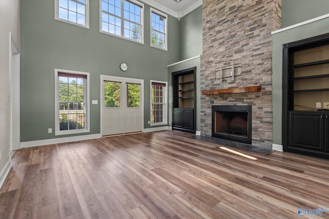 123 Coyote Creek Rd, Meridianville, AL 35759 - unfurnished living room with a towering ceiling, a fireplace, crown molding, wood finished floors, and baseboards