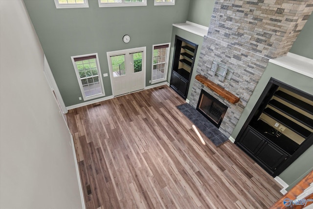 123 Coyote Creek Rd, Meridianville, AL 35759 - unfurnished living room featuring a fireplace, a towering ceiling, wood finished floors, and baseboards