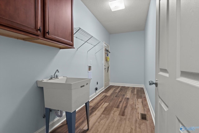 123 Coyote Creek Rd, Meridianville, AL 35759 - laundry area with cabinet space, hookup for a washing machine, baseboards, wood finished floors, and a textured ceiling