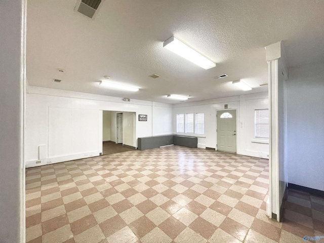 spare room with a textured ceiling, visible vents, and light floors