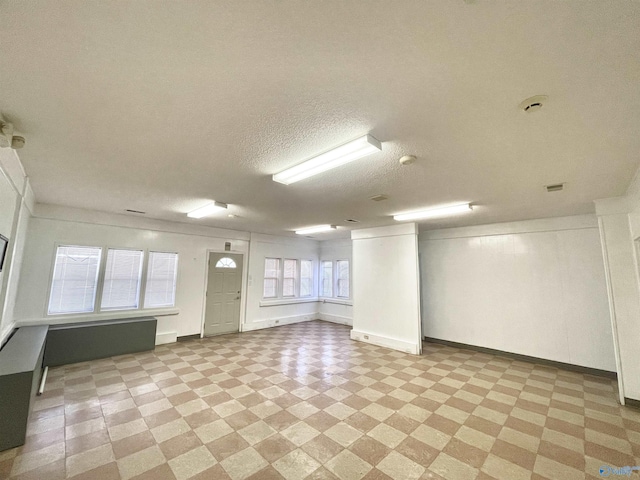 spare room featuring baseboards, light floors, and a textured ceiling