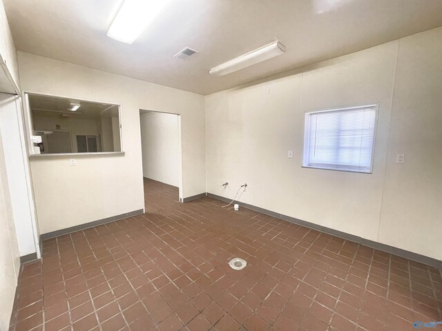 spare room featuring baseboards and brick floor