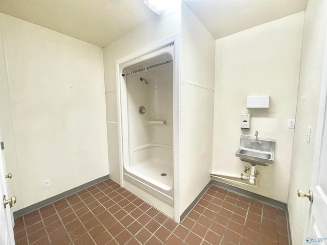 bathroom with a sink, baseboards, and a shower stall