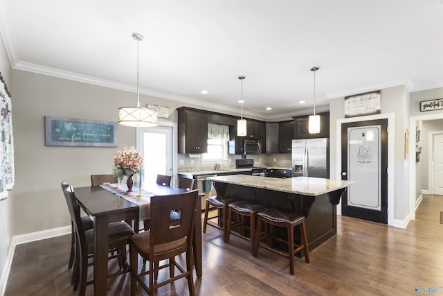 kitchen with appliances with stainless steel finishes, a center island, crown molding, dark hardwood / wood-style floors, and dark brown cabinetry