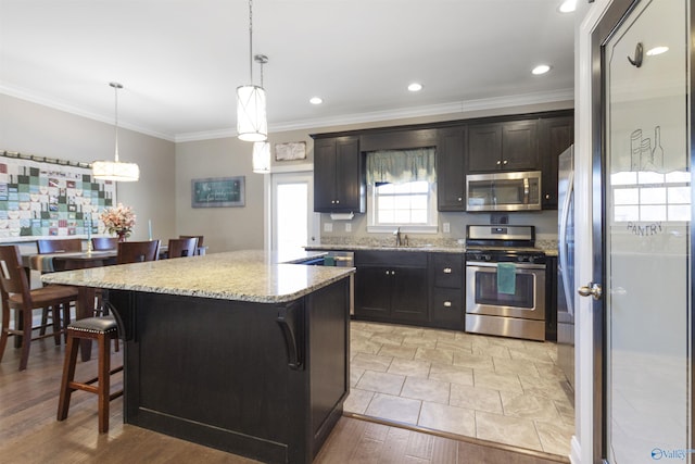 kitchen with sink, a breakfast bar area, a kitchen island, pendant lighting, and appliances with stainless steel finishes