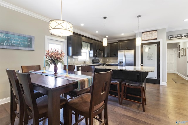 dining space with sink, crown molding, and dark wood-type flooring