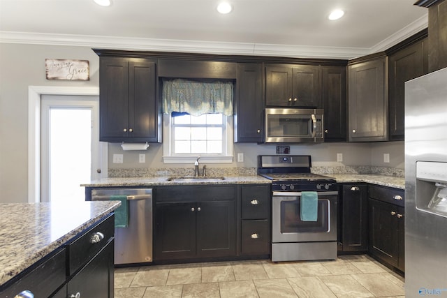 kitchen with appliances with stainless steel finishes, light stone countertops, ornamental molding, sink, and dark brown cabinets