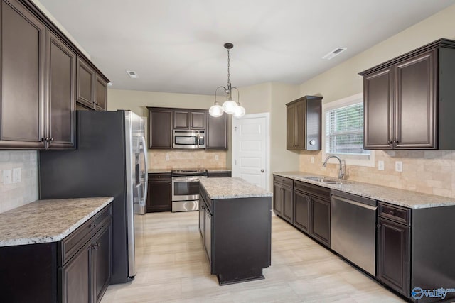 kitchen with sink, tasteful backsplash, appliances with stainless steel finishes, a kitchen island, and pendant lighting