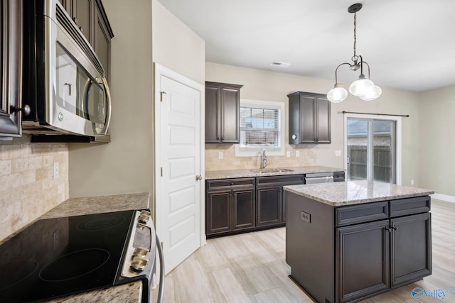 kitchen with dark brown cabinetry, sink, appliances with stainless steel finishes, a kitchen island, and pendant lighting