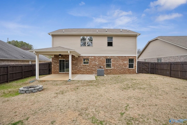 rear view of house with central AC unit, a fire pit, a patio area, and a yard