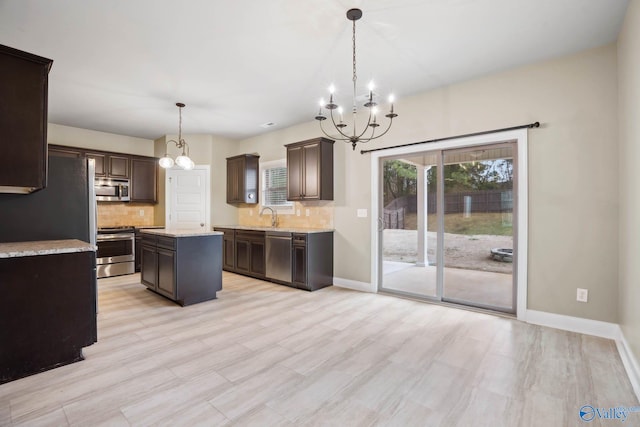 kitchen with dark brown cabinets, appliances with stainless steel finishes, a kitchen island, pendant lighting, and decorative backsplash