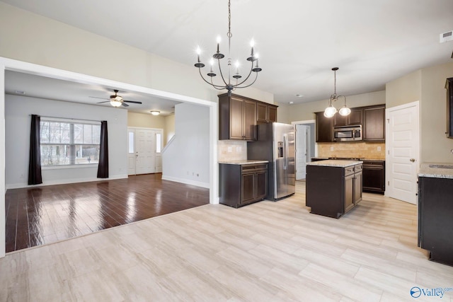 kitchen featuring backsplash, decorative light fixtures, stainless steel appliances, and a kitchen island