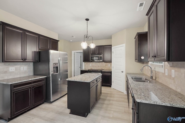 kitchen with decorative light fixtures, sink, backsplash, a center island, and stainless steel appliances