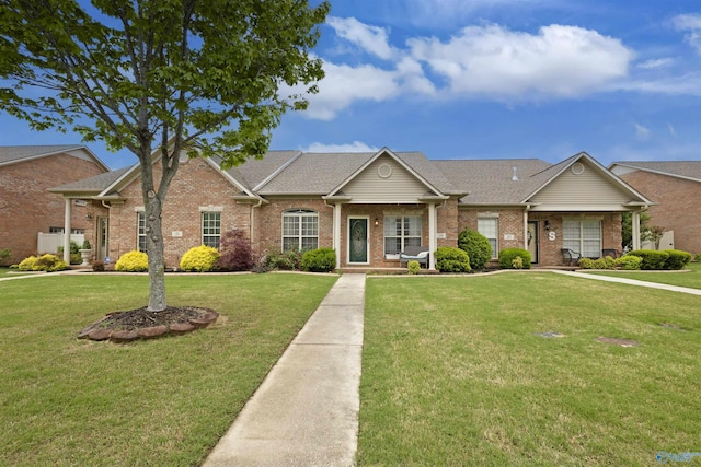 view of front of house with brick siding, roof with shingles, and a front lawn