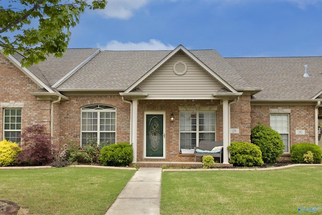 ranch-style house featuring a shingled roof, a front lawn, and brick siding