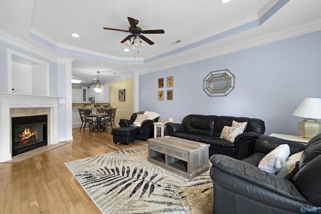 living room with visible vents, decorative columns, hardwood / wood-style floors, a raised ceiling, and a ceiling fan