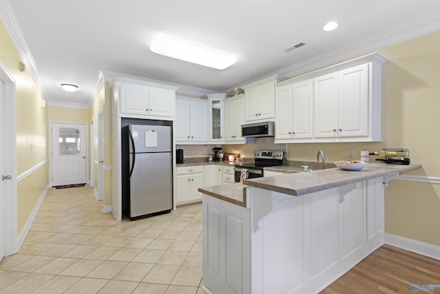 kitchen with ornamental molding, a peninsula, a breakfast bar, baseboards, and stainless steel appliances