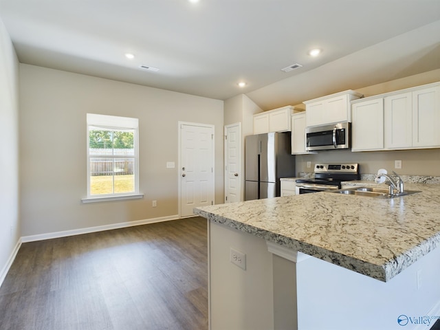 kitchen with sink, light stone counters, appliances with stainless steel finishes, white cabinets, and dark wood-type flooring