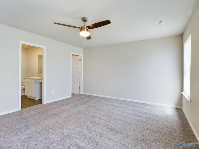 unfurnished bedroom featuring sink, dark colored carpet, ceiling fan, and ensuite bathroom