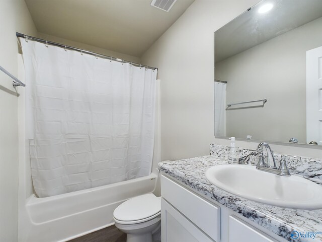 full bathroom featuring vanity, shower / bath combo with shower curtain, and toilet