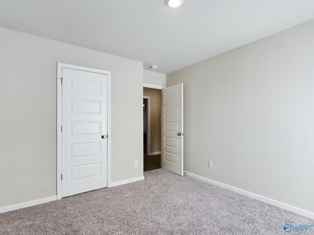 unfurnished bedroom with light colored carpet and a closet