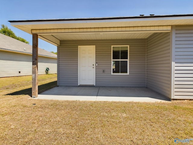 view of exterior entry with a yard and a patio area