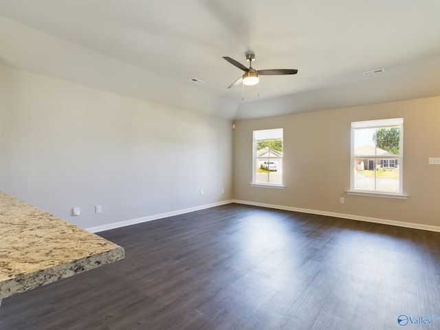 empty room with ceiling fan, a wealth of natural light, and dark hardwood / wood-style floors