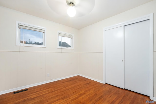 unfurnished bedroom featuring ceiling fan, hardwood / wood-style flooring, and a closet