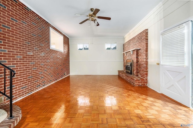 unfurnished living room with light parquet floors, brick wall, and a wealth of natural light