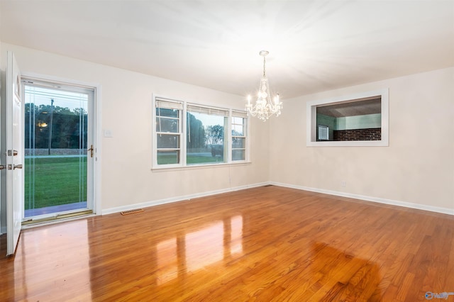 unfurnished room featuring an inviting chandelier and hardwood / wood-style flooring