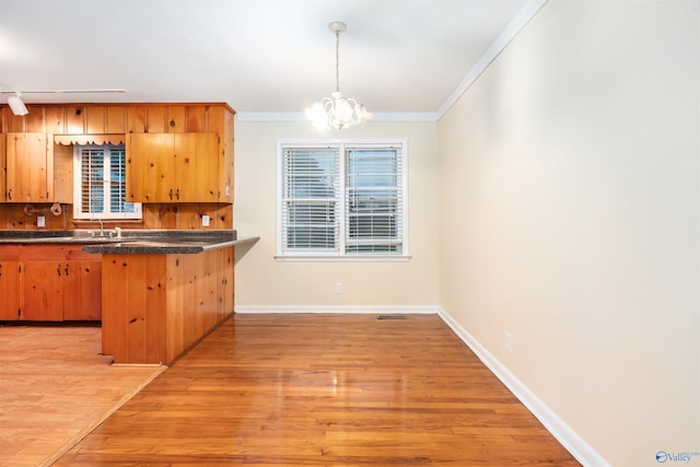 kitchen featuring ornamental molding, light hardwood / wood-style floors, kitchen peninsula, and a chandelier