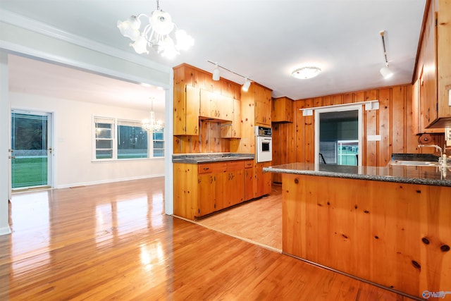 kitchen with light wood-type flooring, a chandelier, track lighting, and white oven