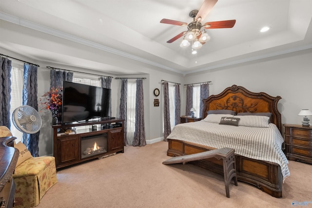 bedroom with a raised ceiling, a fireplace, crown molding, ceiling fan, and light carpet