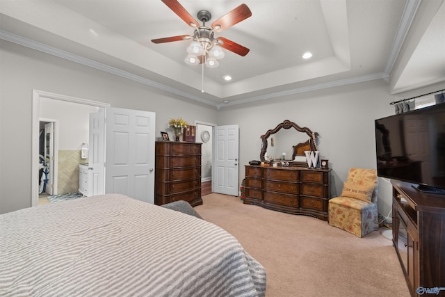 bedroom with light colored carpet, ensuite bath, a raised ceiling, ornamental molding, and ceiling fan