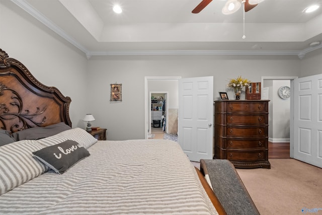 bedroom featuring a tray ceiling, ceiling fan, carpet floors, and crown molding